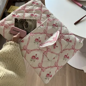 Quilted laptop sleeve detail shot featuring a charming pink ribbon and floral vintage pattern.