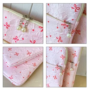 Etui pour ordinateur rose froisse avec noeuds rouges et pendentif perle pour protection chic.
