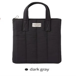 Detail view of the dark gray quilted laptop bag, featuring dual handles and metal accent.