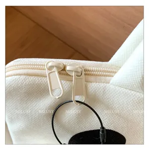 Close-up detail view of white canvas laptop bag zipper, featuring portable sleeve design.