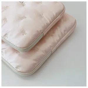 Detailed close-up of pink satin laptop sleeve with cute embroidered bow pattern and zipper.
