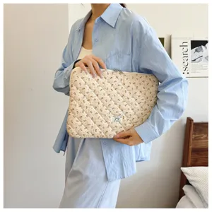 Nahaufnahme einer gesteppten Laptoptasche mit Blumenmuster in der Hand, Detailansicht.