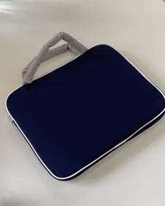 Dunkelblaue Laptoptasche mit grauen Griffen und weißer Paspelierung für den Transport.