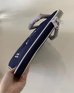 Nahaufnahme einer dunkelblauen Laptoptasche mit weißem Paspel, Griffen und feiner Stickerei.