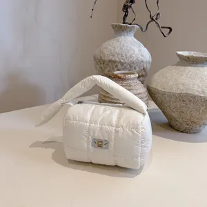 Soft white quilted puffer cosmetic bag, portable travel makeup organizer with knot handle.