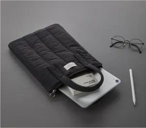 Black quilted laptop sleeve and tablet bag with handles, minimalist design for 11-13 inch devices.