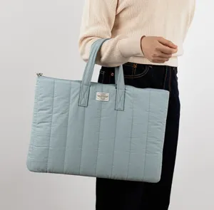 Detail view of the light blue quilted laptop bag with double handles for 13 inch devices.