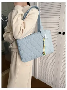Primo piano della borsa tote trapuntata azzurra con motivo a cuori e ciondolo di perline.