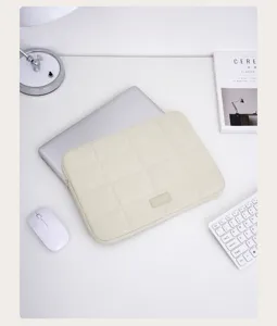 Minimalistische gesteppte Laptoptasche präsentiert auf einem weißen Schreibtisch Detail.