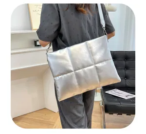 Detail shot of the silver quilted puffer messenger laptop bag with wide strap in modern room.