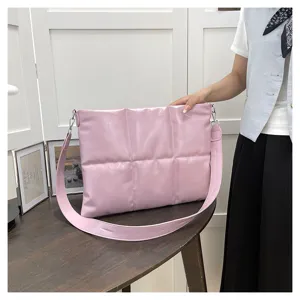 Detailed view of pink quilted laptop shoulder bag, stylish puffer design with wide strap.