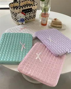 Detailed view of cute quilted heart laptop sleeves with delicate bows in pastel aesthetic setup.