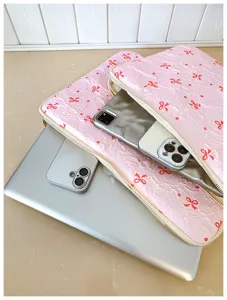 Pink quilted laptop sleeve with cute red bow pattern, stylish padded tablet case for women and girls.
