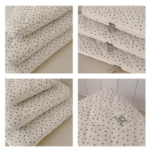 Detailed view of quilted floral laptop sleeve with smooth double zippers and label.