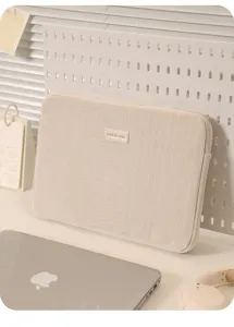 Nahaufnahme der beigen Cord Laptoptasche mit strukturierter Stoff und Markenlabel.