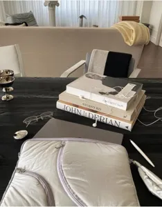 Detail shot of a quilted minimalist laptop sleeve on a dark wooden table in an aesthetic room.