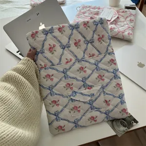 Quilted laptop sleeve with blue bow and pink floral pattern, aesthetic tablet storage bag.