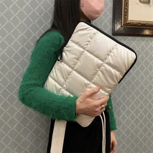 Vista dettagliata della custodia trapuntata bianca per laptop con motivo a rombi e bordo nero.