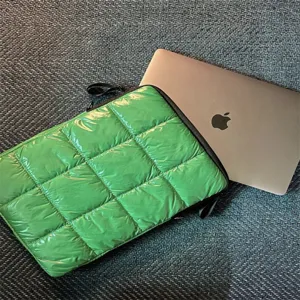 Dettaglio custodia per laptop verde trapuntata, design imbottito morbido per notebook.
