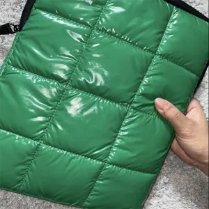 Dettaglio borsa per laptop trapuntata lucida verde, custodia protettiva antiurto imbottita.