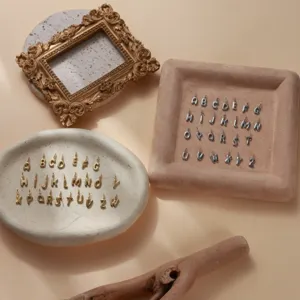 Dettaglio in primo piano di eleganti ciondoli con lettere alfabeto in oro e argento per gioielli.