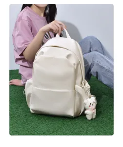 Vista detallada de la mochila minimalista de color sólido con colgante de oso y bolsillo.