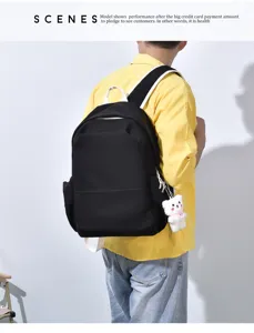 Vista detallada de la mochila escolar negra de gran capacidad con correas blancas y osito.