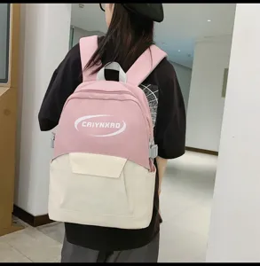 Detail view of the pink and white school backpack, showing stylish color block and front pocket.