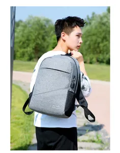 Outdoor detail shot of a grey travel backpack featuring a USB charging port and mesh pocket.