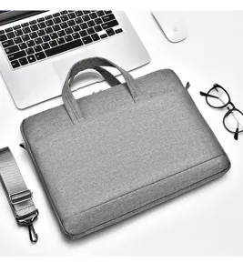 Detailansicht der grauen Laptop-Umhängetasche aus Stoff auf dem weißen Schreibtisch.