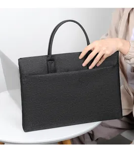 Dettaglio della borsa per laptop in tessuto grigio scuro con manici resistenti e tasca.