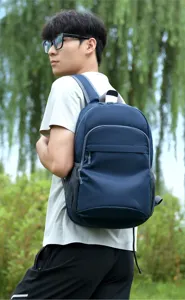 Detailed view of the casual blue outdoor backpack with multiple pockets worn by a model outside.