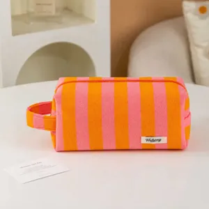 Detailed view of the striped plush cosmetic bag showing soft fabric and handy carry handle.