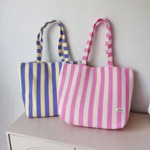Close-up detail view of striped canvas tote bags in yellow and pink, casual large capacity.