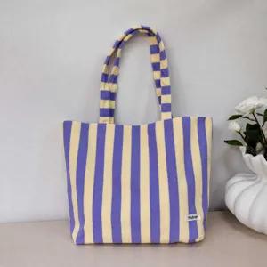 Detailed view of the purple and yellow striped canvas tote bag, showing fabric texture and strap.