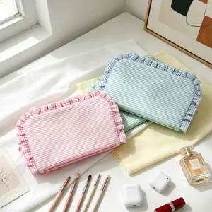 Striped seersucker cosmetic bag with cute ruffle trim, portable travel makeup pouch organizer.