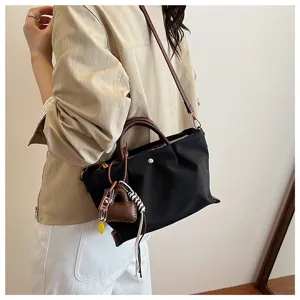 Casual minimalist black nylon women's shoulder bag with brown leather handles and heart charm.