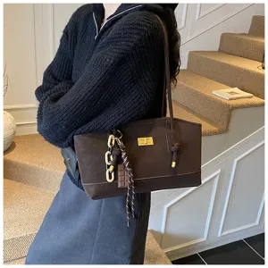 Detail shot of the brown suede shoulder bag with gold turn-lock and chain decor.