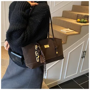 Brown leather shoulder tote bag with metal twist lock and chic bag charms for women daily wear.