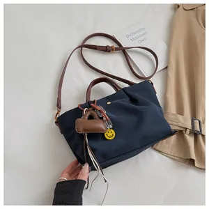 Casual navy blue shoulder bag with brown straps, cute charms, and pleated design for daily use.