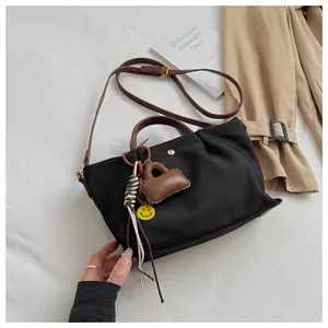 Detail view of the black canvas crossbody bag with brown straps and cute bag charms.
