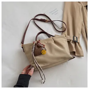 Casual khaki canvas shoulder handbag for women commuter crossbody bag with cute charms.