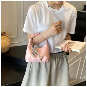 Rosa gefaltete Schultertasche Detailansicht, stilvolle Handtasche mit Metall-Anhänger.