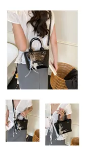 Detailed view of women black patent leather crossbody bag with chic silver heart charm and handles.