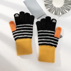 Gants tricotés tactiles d'hiver à rayures noires et blanches et poignets jaunes chauds.