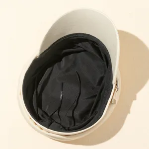 Détail intérieur de casquette gavroche beige, chapeau plat rétro chic avec doublure noire.