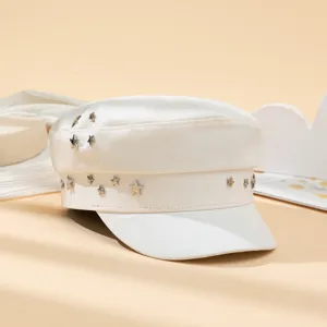 Détail de casquette gavroche blanche avec des étoiles métalliques, très tendance.
