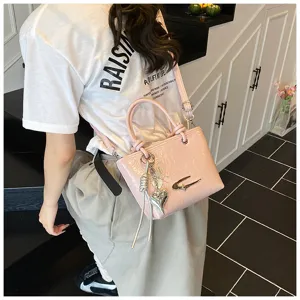 Chic pink patent leather handbag featuring metal heart and butterfly charms for women.