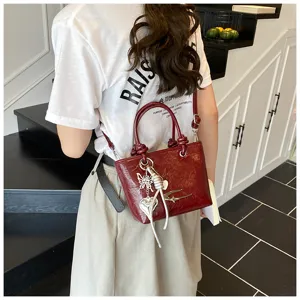 Burgundy patent leather small handbag with metal charms, stylish retro crossbody tote bag.