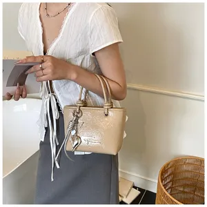 Vintage glossy small tote bag for women, stylish handbag with metal charm and dual handles.